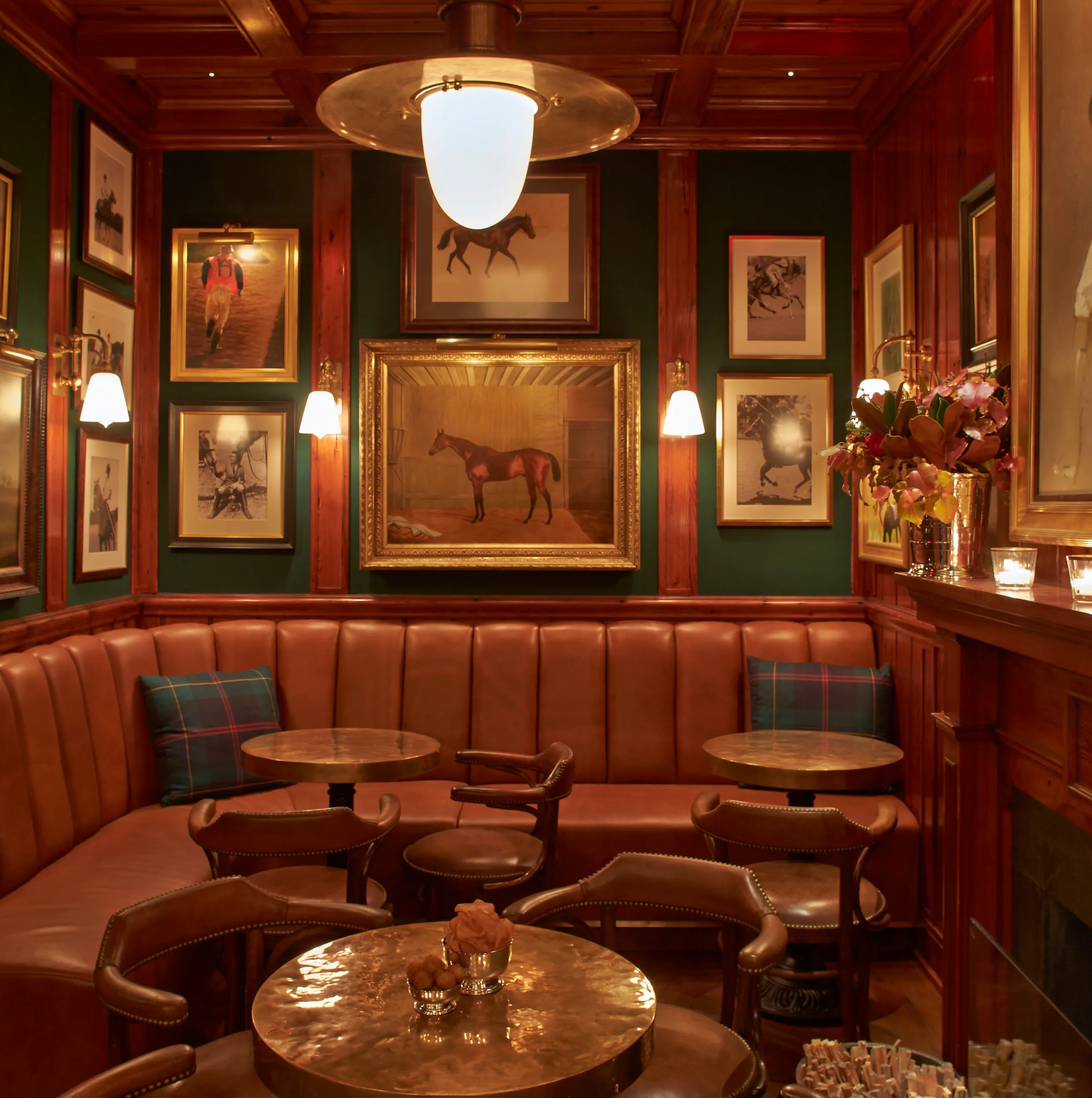 Decorative interior of a bar with leather booths, framed pictures, and a horse portrait.