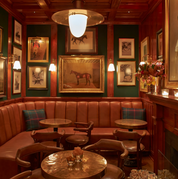 Decorative interior of a bar with leather booths, framed pictures, and a horse portrait.