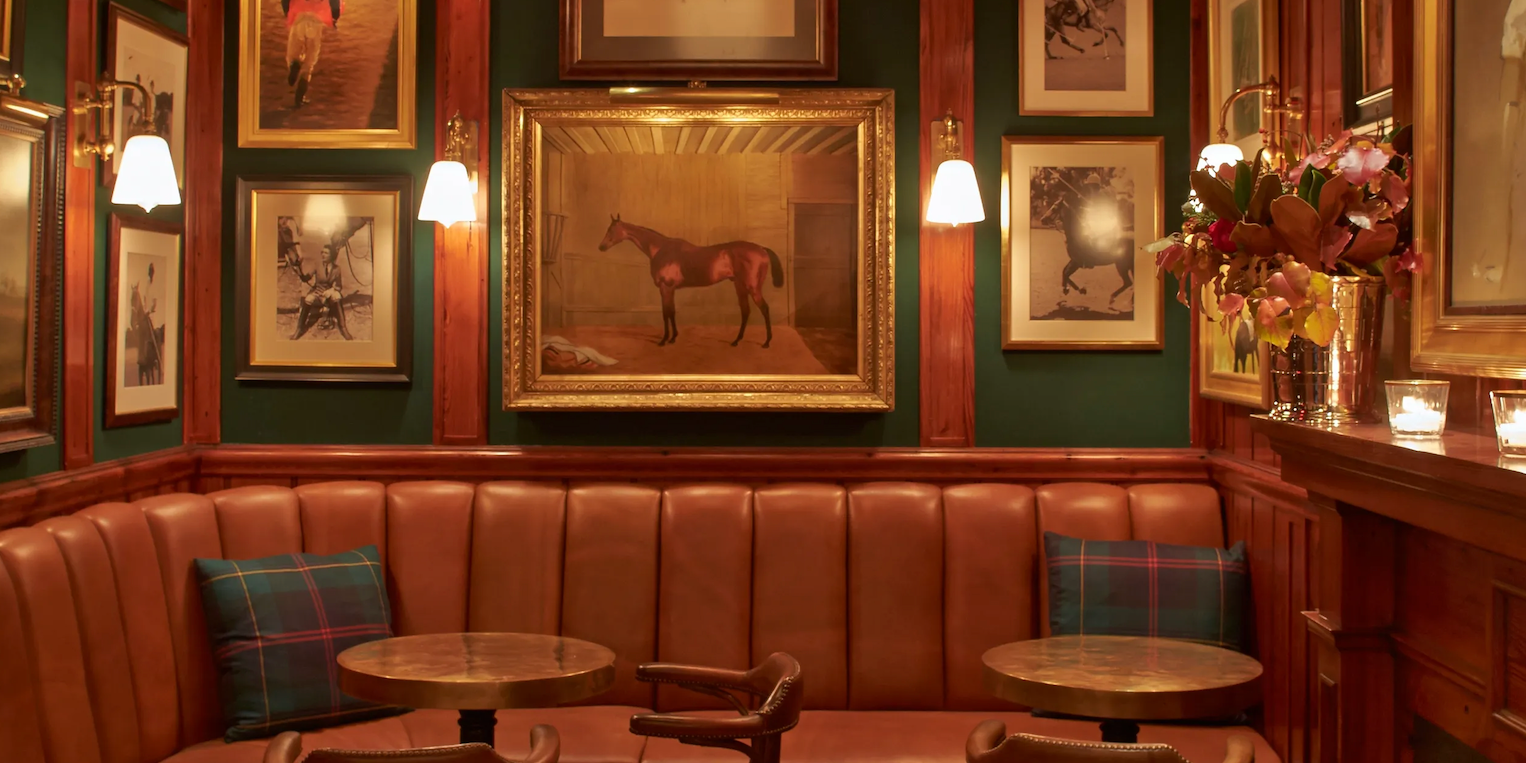 Decorative interior of a bar with leather booths, framed pictures, and a horse portrait.