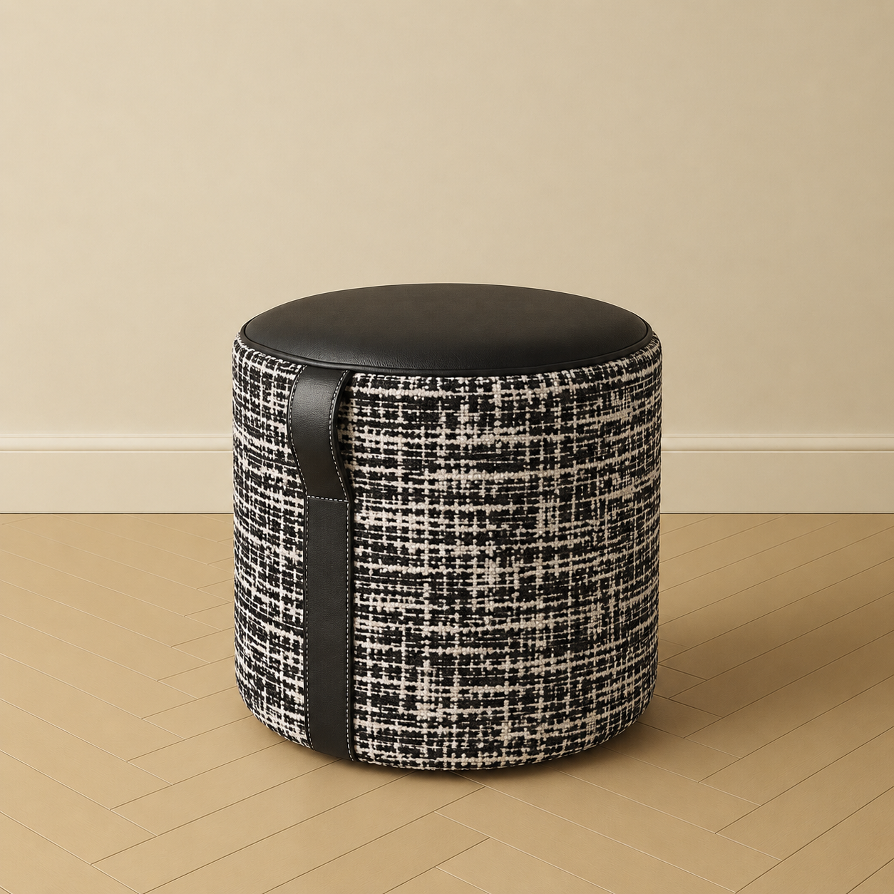 18 inch round ottoman with black leather top, signature leather handle, and black and ivory woven upholstery
