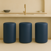 blue Modern round bar stool in full-grain leather with minimalist cylindrical shape placed in a neutral-toned luxury kitchen