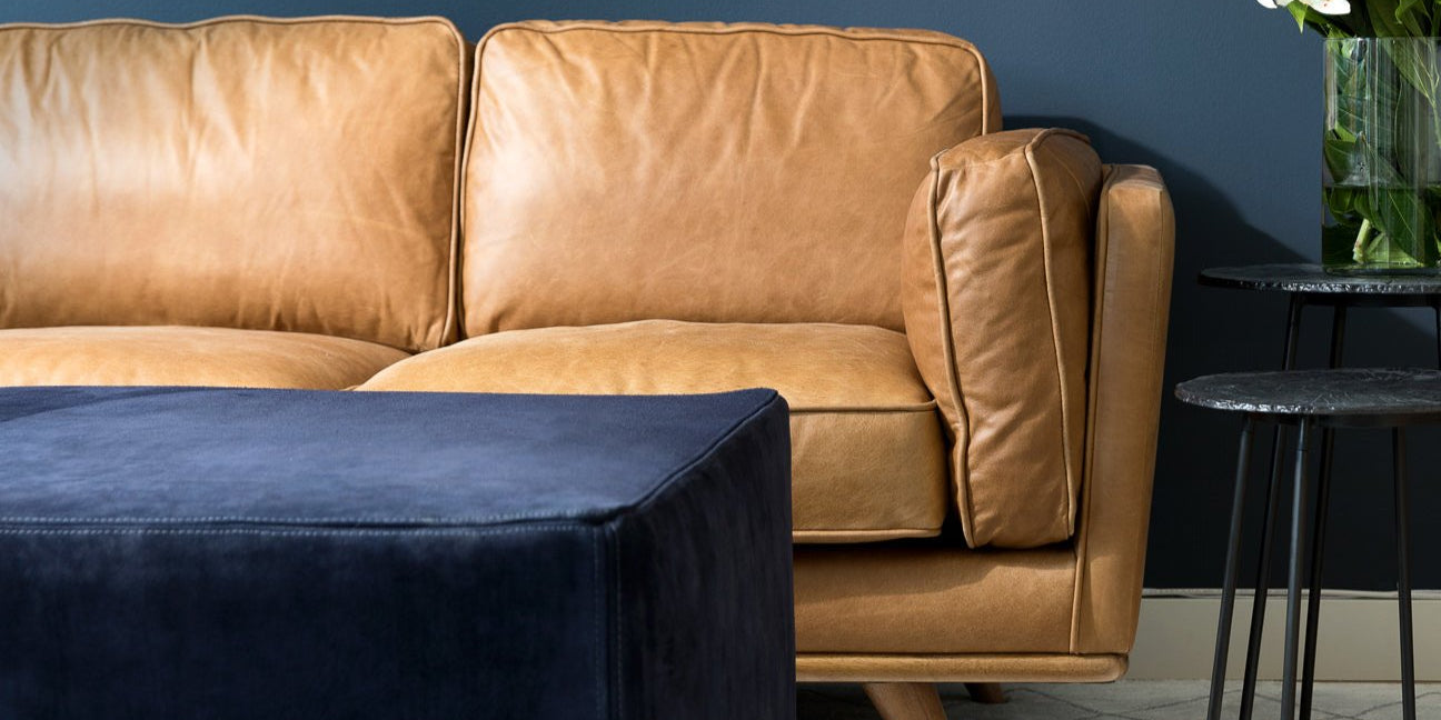 leather sofa against blue wall with suede ottoman