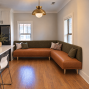 HF Atelier custom L-shaped dining banquette in cognac leather and olive velvet with recessed maple legs