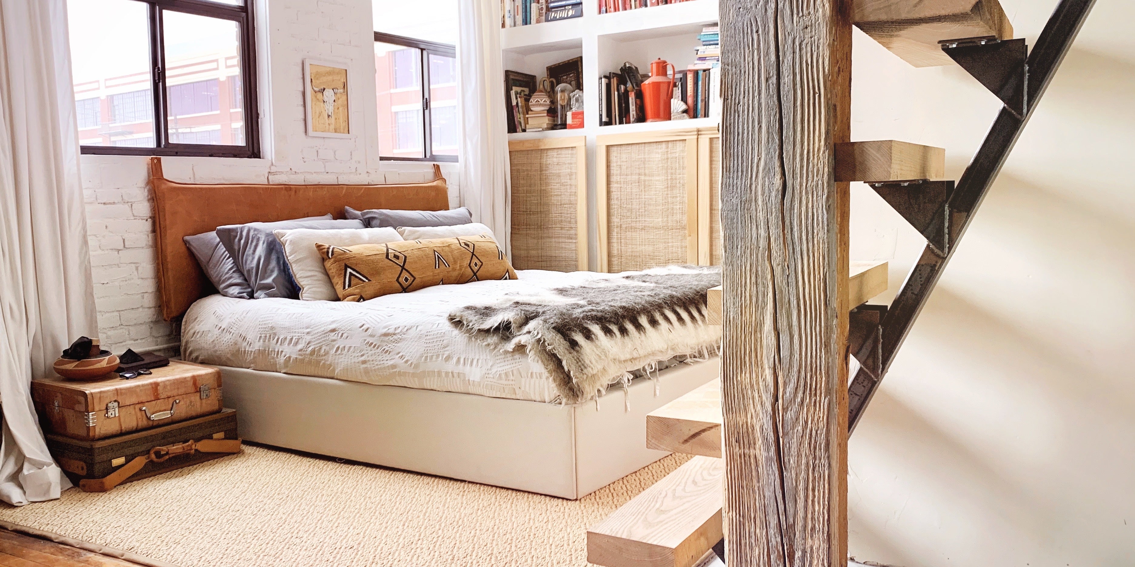 Full-grain brown leather wall-mounted headboard with topstitching, styled on a king bed in a modern space-saving design